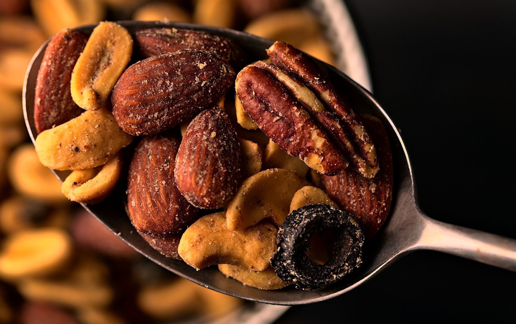 A spoon full of nuts on top of a table.